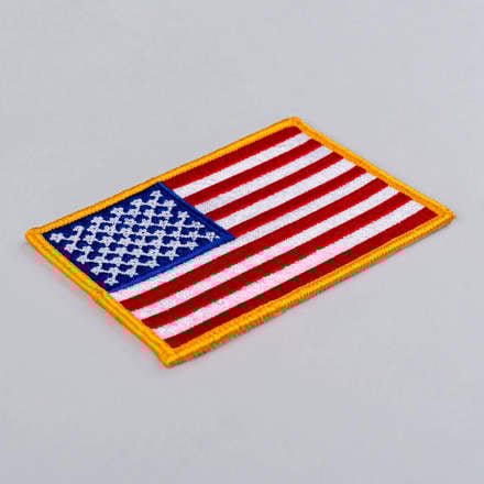 Embroidered American Flag Patch with yellow border laid at a hard angle